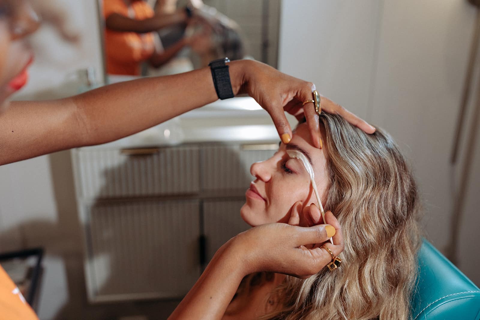 A beautician applies a brow treatment to a client, carefully shaping and grooming the eyebrow in a spa setting