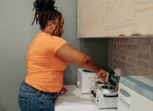 A technician prepares a waxing station, stirring a pot of wax in a professional spa setting